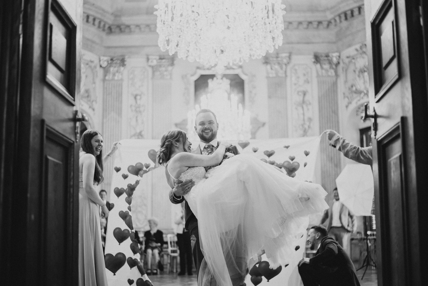 Bräutigam trägt Braut über Schwelle zum Festsaal bei Hochzeitsreportage
