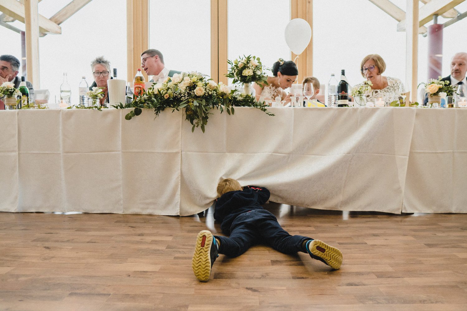 Hochzeitsreportage Weingut Schlossberg Kind liegt am Boden und schaut unter den Tisch